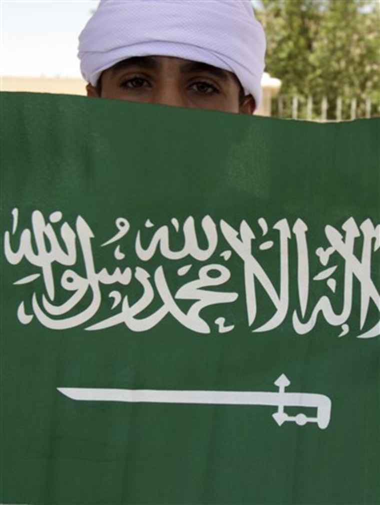 A schoolboy displays a Saudi flag at a bus stop in Hamad Town, Bahrain, west of the capital of Manama.